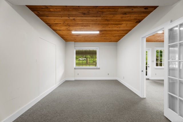 spare room with a wealth of natural light, carpet, and wooden ceiling