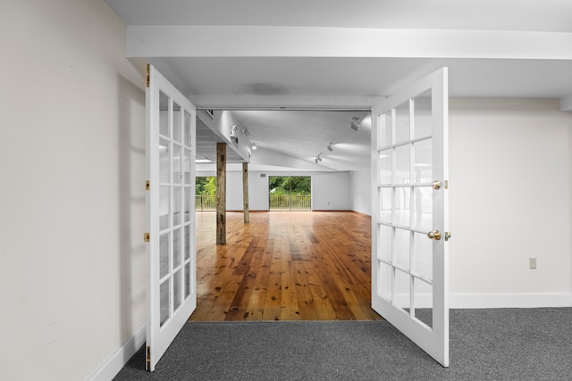 hallway with french doors, vaulted ceiling, and wood-type flooring