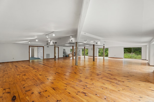 unfurnished living room featuring rail lighting, light hardwood / wood-style floors, and vaulted ceiling