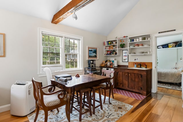 dining room featuring light hardwood / wood-style flooring and vaulted ceiling with beams