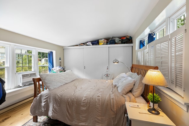 bedroom featuring cooling unit, hardwood / wood-style flooring, and vaulted ceiling