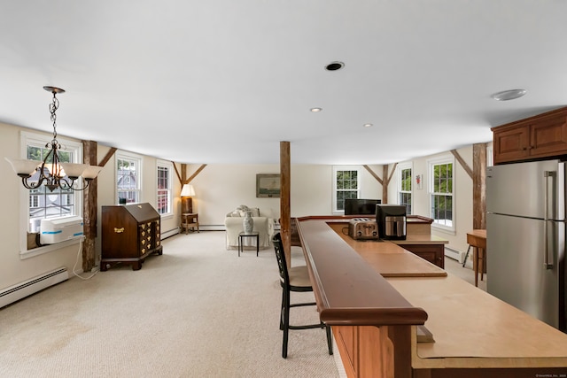 kitchen featuring decorative light fixtures, stainless steel fridge, a notable chandelier, and a healthy amount of sunlight