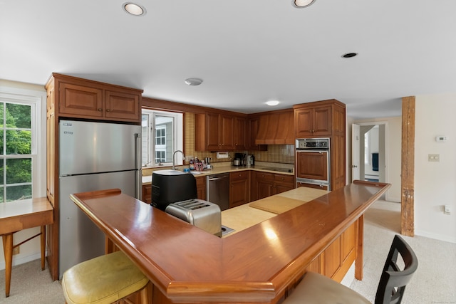 kitchen with stainless steel appliances, sink, light carpet, and decorative backsplash