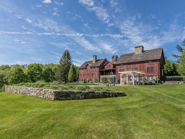 back of house with a pergola and a lawn