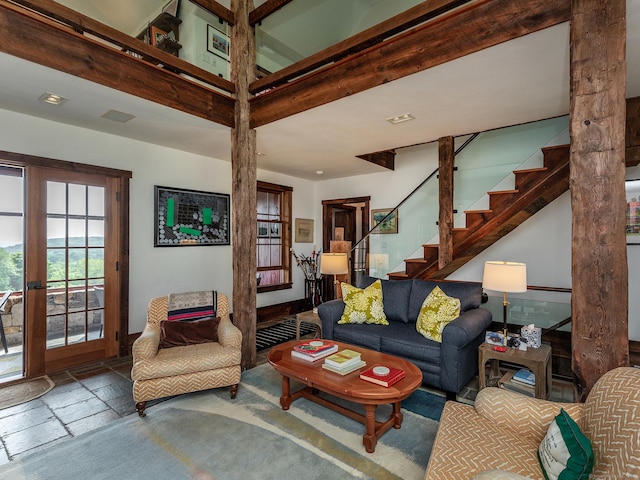 living area with stairs, ornate columns, and stone tile flooring
