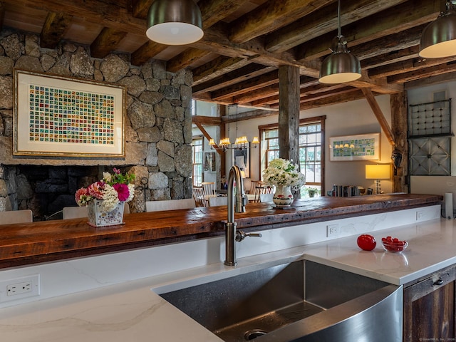 kitchen featuring pendant lighting, an inviting chandelier, butcher block counters, and sink