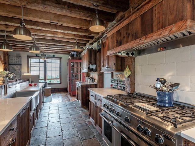 kitchen with pendant lighting, high end range, a sink, beamed ceiling, and light countertops