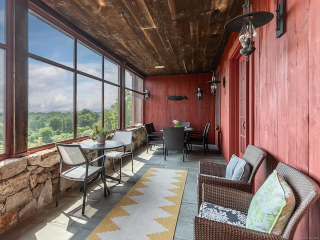 sunroom with wood walls, wood ceiling, outdoor dining area, and a wealth of natural light