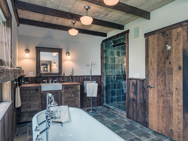 bathroom featuring stone finish flooring, a shower stall, a freestanding tub, a wainscoted wall, and beam ceiling