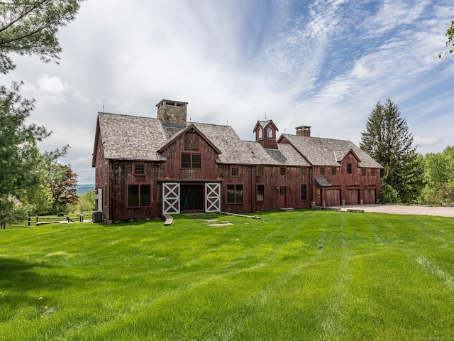 view of front of home with driveway, a front lawn, a chimney, and a barn