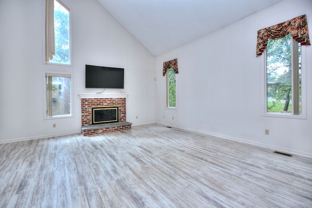 unfurnished living room featuring light wood-type flooring, a fireplace, and high vaulted ceiling