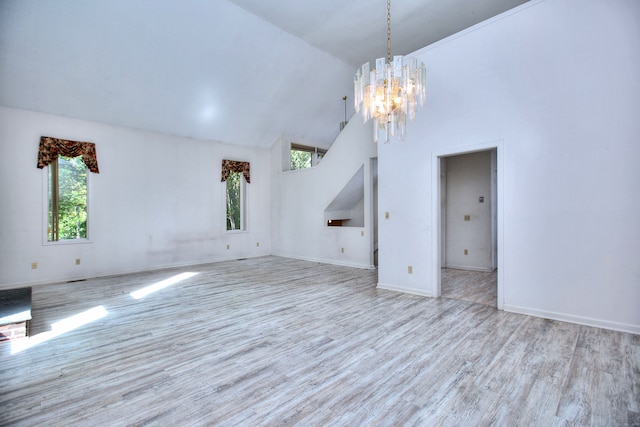 unfurnished living room with light hardwood / wood-style flooring, a notable chandelier, and high vaulted ceiling