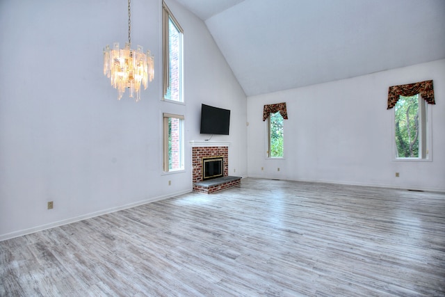 unfurnished living room featuring an inviting chandelier, a brick fireplace, and plenty of natural light