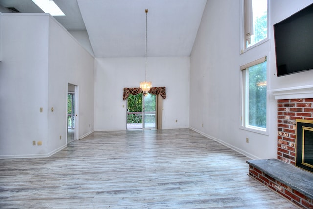 unfurnished living room featuring a brick fireplace, light hardwood / wood-style floors, and plenty of natural light