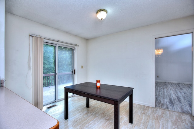 dining area with a textured ceiling, light hardwood / wood-style flooring, and a chandelier