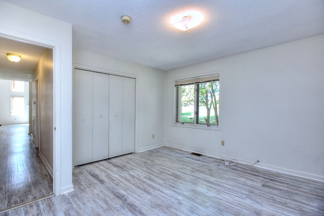 unfurnished bedroom featuring a textured ceiling, light hardwood / wood-style flooring, and a closet