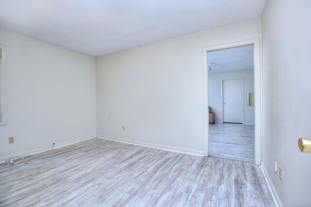 spare room with a textured ceiling and light hardwood / wood-style floors