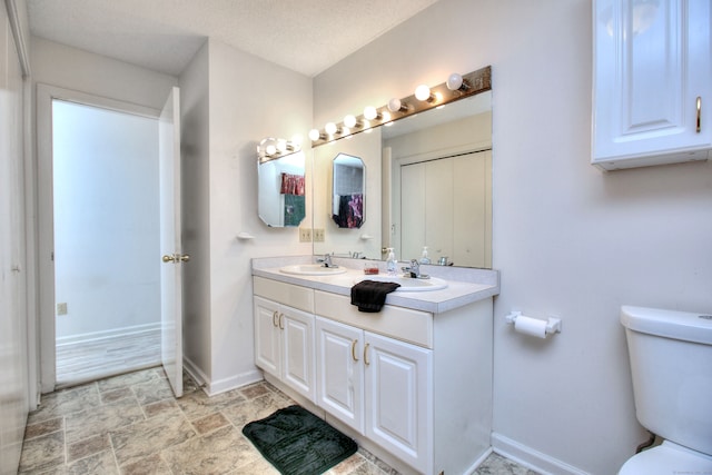 bathroom with a textured ceiling, vanity, and toilet