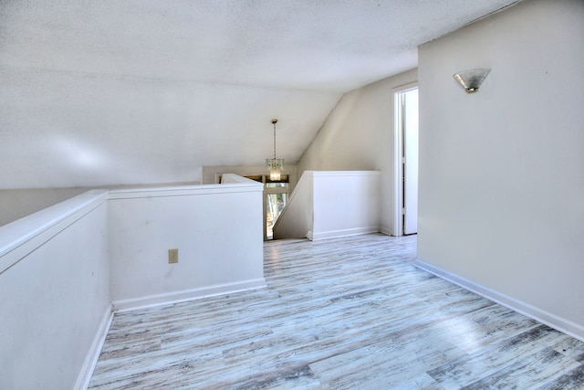 interior space featuring a textured ceiling, light hardwood / wood-style flooring, and vaulted ceiling