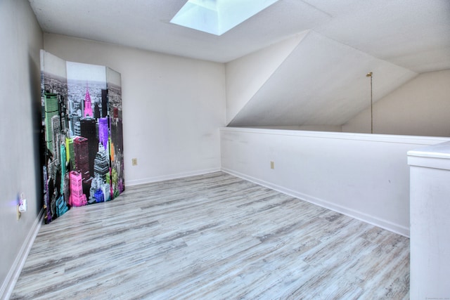 unfurnished room featuring light wood-type flooring and vaulted ceiling with skylight