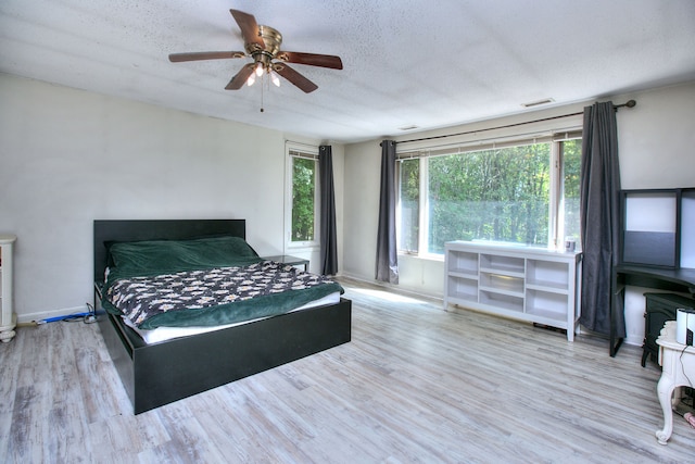 bedroom with a textured ceiling, ceiling fan, and light hardwood / wood-style flooring