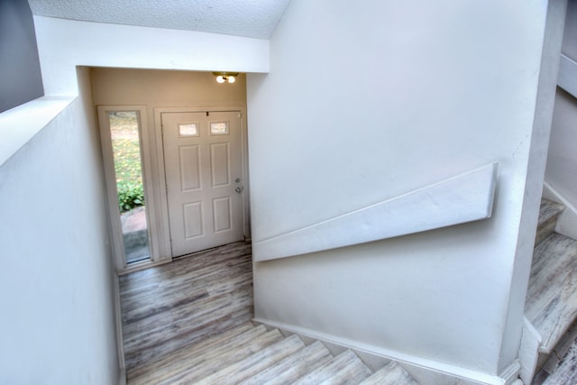 foyer entrance with a textured ceiling and light hardwood / wood-style flooring