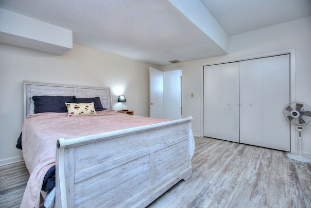 bedroom featuring a closet, light hardwood / wood-style floors, and a textured ceiling