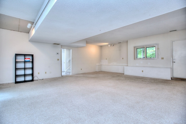 unfurnished living room featuring a textured ceiling and light colored carpet