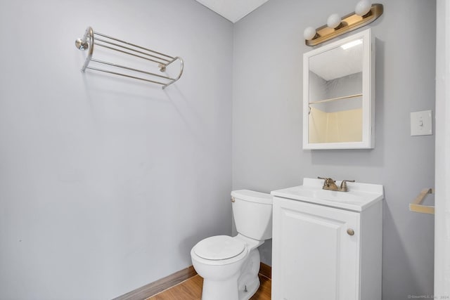 bathroom with toilet, wood finished floors, and vanity