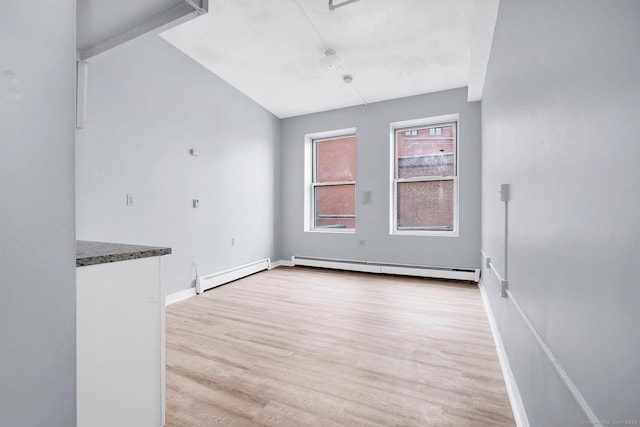 empty room with a baseboard heating unit, a baseboard radiator, baseboards, and light wood finished floors