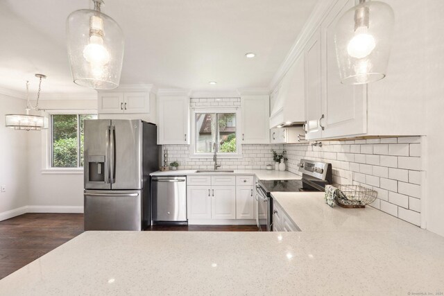 kitchen featuring light stone counters, stainless steel appliances, sink, decorative light fixtures, and white cabinets