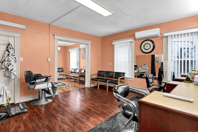 home office featuring a wall mounted AC, a textured ceiling, and hardwood / wood-style floors