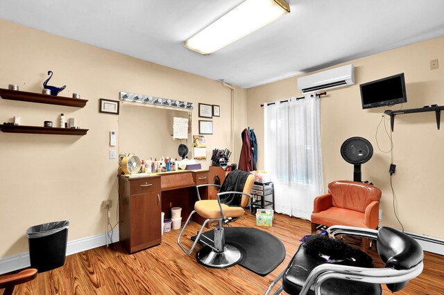 office area featuring light wood finished floors, a wall mounted air conditioner, and baseboards