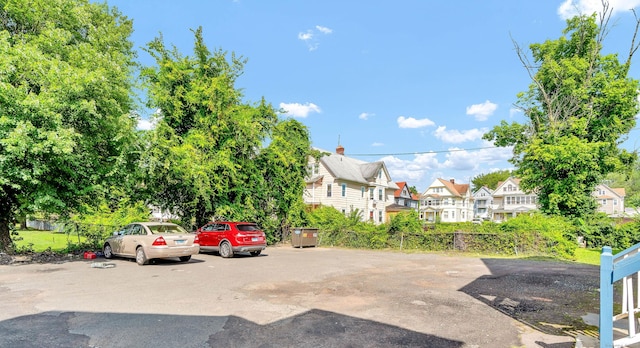 view of vehicle parking featuring a residential view and fence