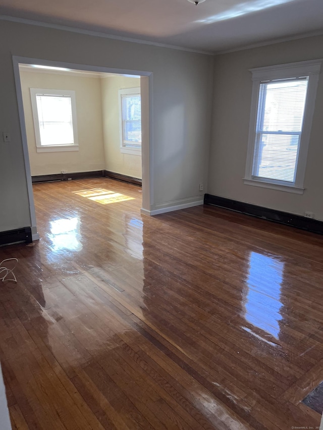 spare room with baseboards, ornamental molding, and dark wood finished floors