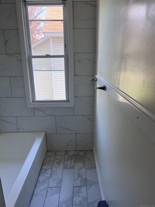 bathroom featuring a tub and marble finish floor