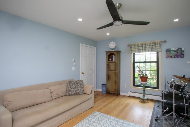 living room featuring a baseboard radiator, ceiling fan, and light wood-type flooring