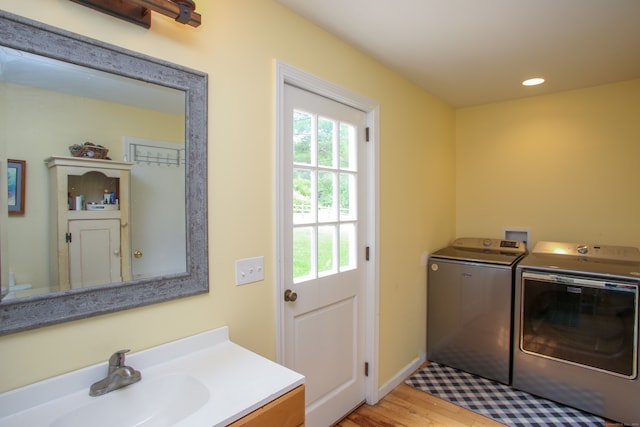 clothes washing area featuring light hardwood / wood-style floors, sink, and washing machine and clothes dryer