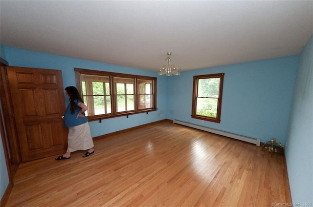 unfurnished bedroom featuring light hardwood / wood-style floors, a baseboard radiator, and a chandelier