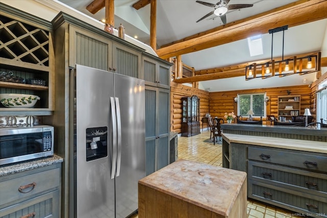 kitchen featuring rustic walls, a kitchen island, ceiling fan, appliances with stainless steel finishes, and decorative light fixtures