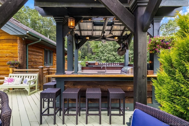 wooden terrace with an outdoor bar and ceiling fan