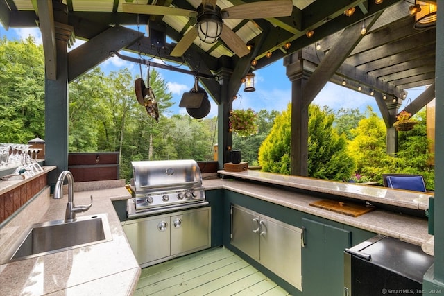 view of patio / terrace with exterior kitchen, a pergola, ceiling fan, sink, and grilling area