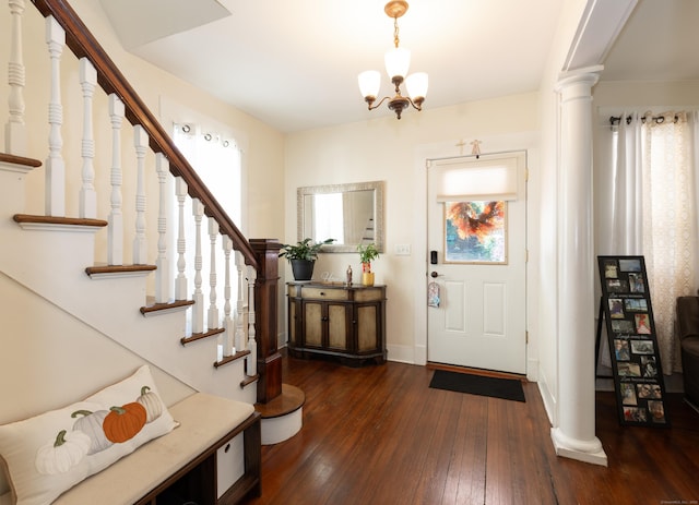 foyer with dark hardwood / wood-style floors, a notable chandelier, and decorative columns