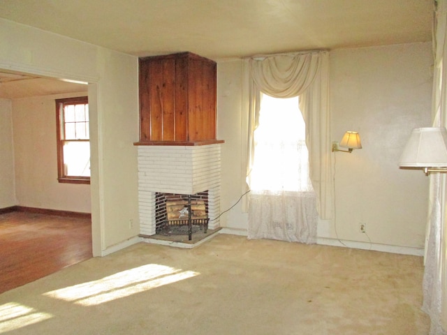 unfurnished living room with plenty of natural light, light carpet, and a brick fireplace