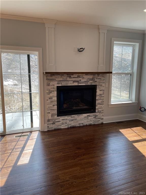 unfurnished living room featuring ornamental molding, dark hardwood / wood-style flooring, and a stone fireplace