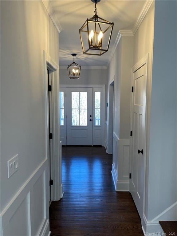 doorway with ornamental molding, dark hardwood / wood-style flooring, and a chandelier