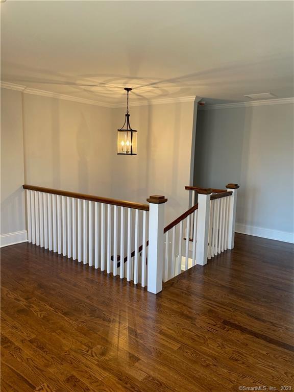 stairs featuring crown molding, a chandelier, and hardwood / wood-style flooring