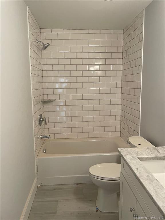 full bathroom featuring vanity, hardwood / wood-style floors, tiled shower / bath combo, and toilet