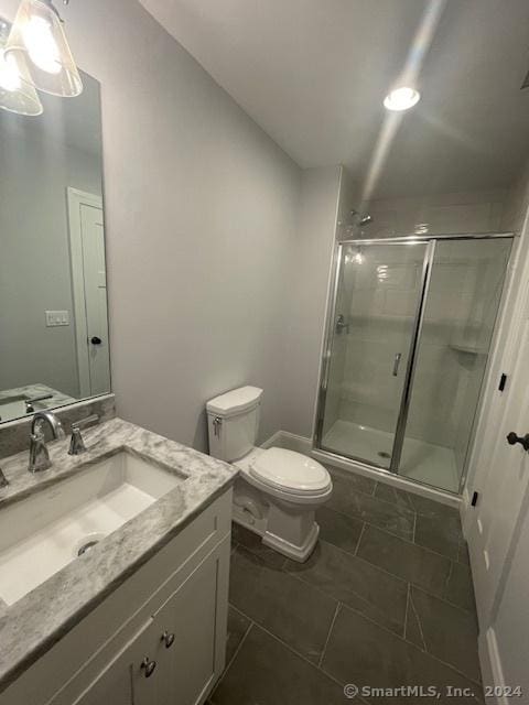 bathroom featuring vanity, a shower with door, and toilet