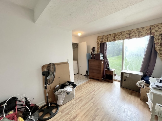 miscellaneous room featuring a textured ceiling, light hardwood / wood-style flooring, and washing machine and clothes dryer